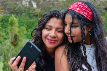 Two young women taking a selfie in nature with smartphone