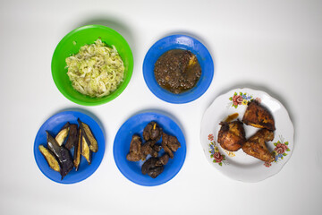 A variety of colorful traditional dishes, including fried chicken, cabbage, eggplant and pepper sauce.