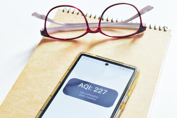 Mobile phone screen showing very unhealthy air quality outdoor. Purple code, health warning. Environmental issue, air pollution. Digital display, selective focus.