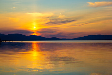 Golden sunset over tranquil lake with colorful sky and smooth reflections. Serene evening scene...