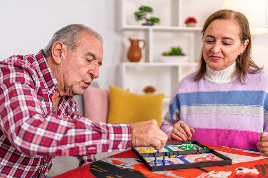 Concentrated senior couple playing board game at home
