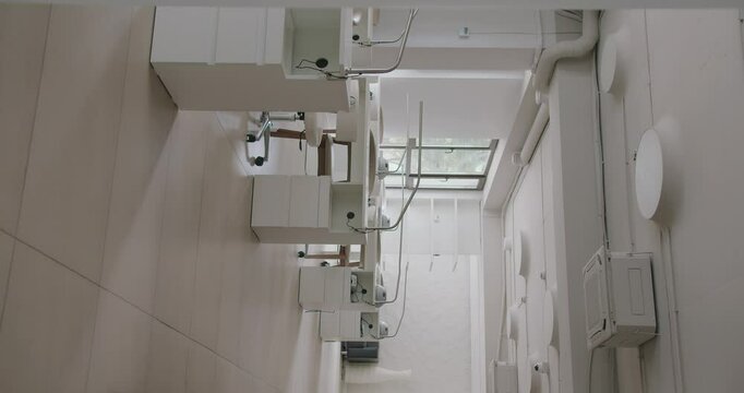 Spacious beauty salon with modern interior, comfort workplaces with tables, chairs and professional equipment for nail masters. Stylish empty nail studio in light tones. Vertical video