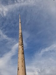 A vertical view of a tall, slender pole, likely a flagpole or utility pole, extending into a vast...
