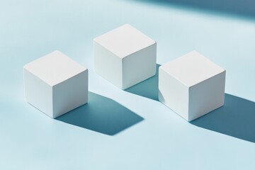 Fototapeta premium Three white cubes on light blue surface, casting shadows