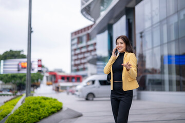 Naklejka premium Businesswoman walking and talking on phone in city center