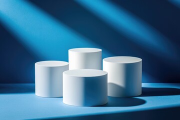 Four white cylinder pedestals on a bright blue surface, bathed in sunbeams