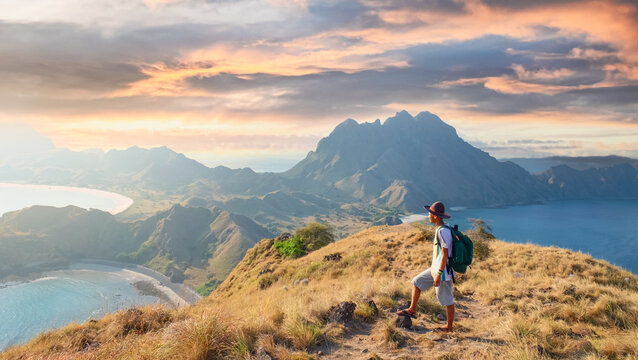 Man hiking to hilltop with breathtaking ocean and mountain view at Padar Island, Komodo Indonesia. Perfect summer vacation and adventure stock photo. - Powered by Adobe
