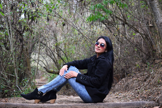 Sesi&oacute;n de fotos de invierno, chica bonita usando un abrigo negro, pantal&oacute;n azul y zapatos negros. Concepto de moda, belleza y estilo.