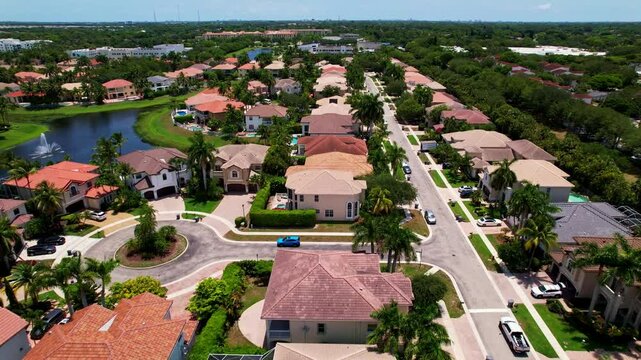 Dolly in drone shot of residential area and lake during the day with road and palm trees in West Palm Beach, Florida, USA