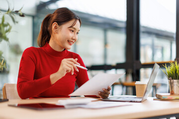 Smiling Asian Business woman using calculator and laptop for doing math finance on an office desk,...
