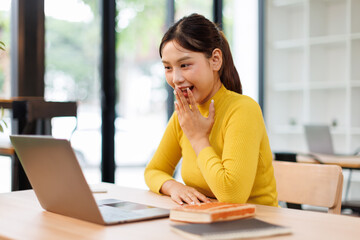 Obraz premium Happy young Asian business woman celebrating success at work in office looking at laptop excited about financial trading growth, goals achievement good online results, screaming yes watching game. 