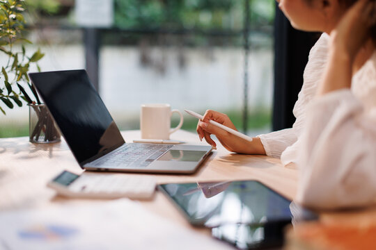 Portrait of business Young Asian woman  is sitting at a desk with a laptop open in front of her. She is thinking and planning his project, remote working at workplace.
