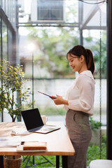 Portrait of business Asian woman Accounting using tablet calculating income-expenditure and...