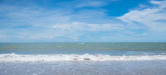 Waves on the beach. Blue sky with white clouds. Panorama.