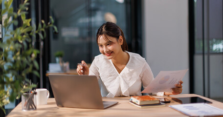 Cheerful Young business Asian businesswoman working on desk office with using a calculator document...