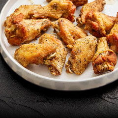 Tasty lemon pepper chicken wings served on a white plate. Crispy golden skin, seasoned with black pepper and citrus zest. Ideal for menus, food blogs, party or BBQ themes.