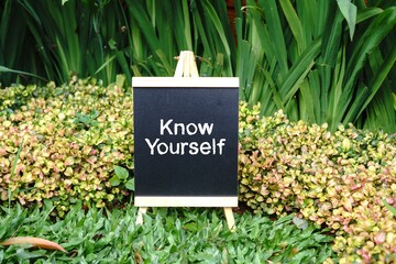 Know Yourself writing concept on a small blackboard with a background of trees.