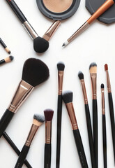 Makeup brushes and tools arranged on white background, featuring various sizes and shapes for different cosmetic applications