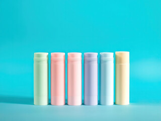 Pastel colored cylindrical containers arranged in row on blue background, evoking clean and minimal aesthetic