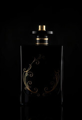 Elegant black perfume bottle with gold decorative swirls on dark background, exuding luxury and sophistication