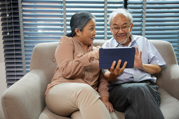 Senior couple smiling and video chatting on tablet at home