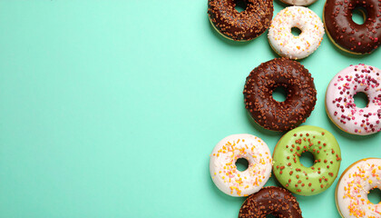 Colorful glazed donuts with sprinkles arranged on mint green background with clean space on left, creating cheerful and appetizing scene for dessert lovers