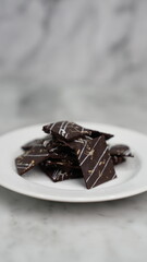 Crispy brownies arranged on a glass jar and white ceramic plate with a white marble background....