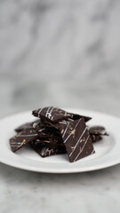 Crispy brownies arranged on a glass jar and white ceramic plate with a white marble background....