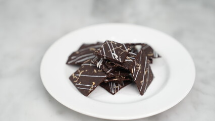Crispy brownies arranged on a glass jar and white ceramic plate with a white marble background....