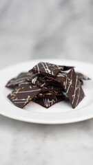 Crispy brownies arranged on a glass jar and white ceramic plate with a white marble background....