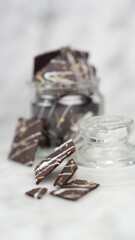 Crispy brownies arranged on a glass jar and white ceramic plate with a white marble background....