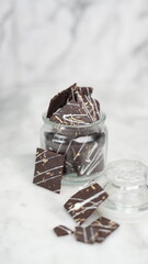 Crispy brownies arranged on a glass jar and white ceramic plate with a white marble background....