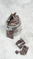 Crispy brownies arranged on a glass jar and white ceramic plate with a white marble background....