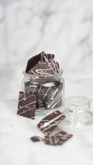Crispy brownies arranged on a glass jar and white ceramic plate with a white marble background....