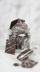 Crispy brownies arranged on a glass jar and white ceramic plate with a white marble background....