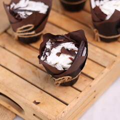 catherine chocolate cake wrapped in brown cake paper and tied with hemp rope, arranged on a hollow wooden baking tray