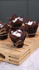 catherine chocolate cake wrapped in brown cake paper and tied with hemp rope, arranged on a hollow wooden baking tray