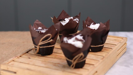 catherine chocolate cake wrapped in brown cake paper and tied with hemp rope, arranged on a hollow wooden baking tray