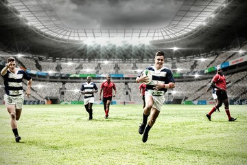 Two teams of rugby players playing rugby in sports stadium