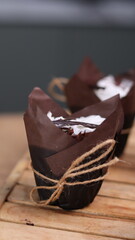 catherine chocolate cake wrapped in brown cake paper and tied with hemp rope, arranged on a hollow wooden baking tray