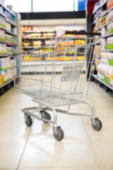 Shopping cart on aisle amidst products on shelves in supermarket