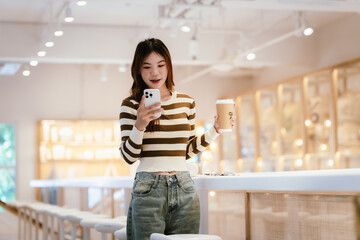 A young woman wearing headphones and glasses, appearing to be an East Asian female, intently uses a white laptop at a cafe table.