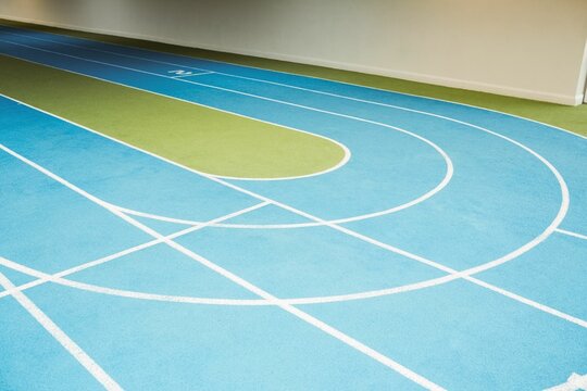 Fototapeta Curved synthetic running track is being shown in flat design, featuring blue lanes with green turf