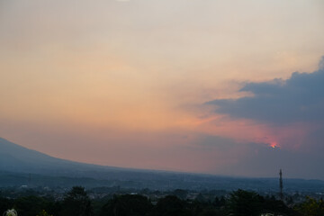 Golden sunset bathes Mount Salak in a soft glow as evening descends over Bogor, West Java, creating...