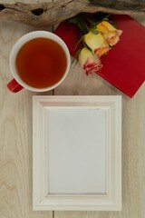 Photo frame, lemon tea, diary and flowers on wooden table