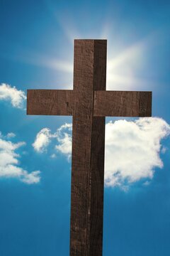 Flat design is featuring rough wooden cross against blue sky with clouds, sun casting halo glow