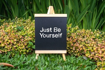 Just Be Yourself writing concept on a small blackboard with a background of trees.