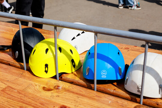 Multicolored mountaineering helmets lie on a wooden table.