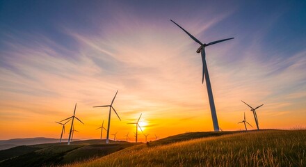 Obraz premium Wind turbines on a grassy hill at sunset with a colorful sky and golden light shining behind them all