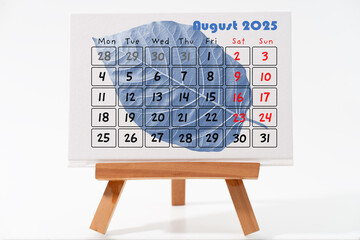 Calendar August 2025 on textured standing canvas with green leaf in the background with, the canvas...